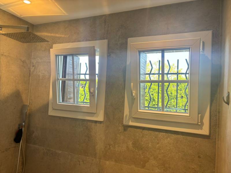 Vue intérieure de deux fenêtres PVC avec vitrage décoratif et grilles de sécurité – Pose soignée signée KCM Menuiserie à Plan d’Orgon